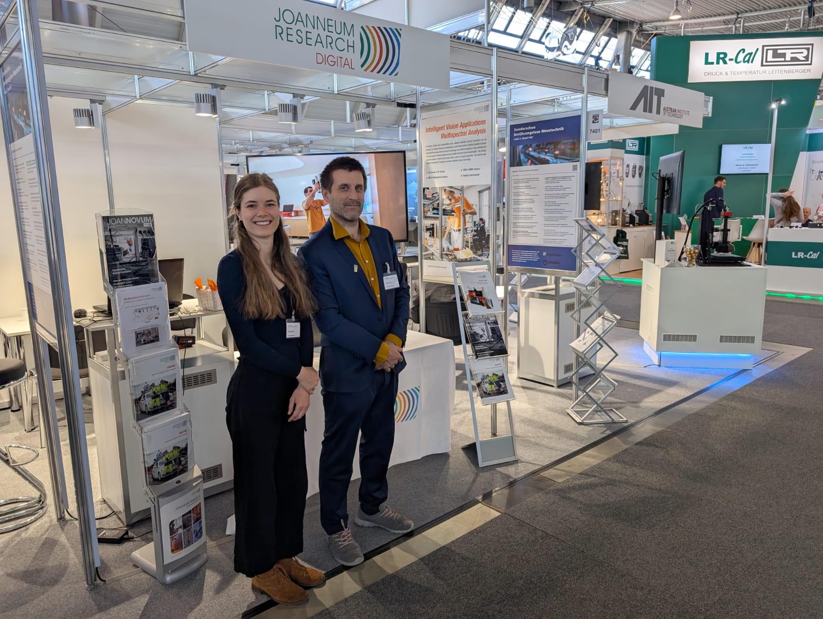 Gerald Lodron und Maria Jernej vor dem JOANNEUM RESEARCH Stand auf der Messe Control in Stuttgart